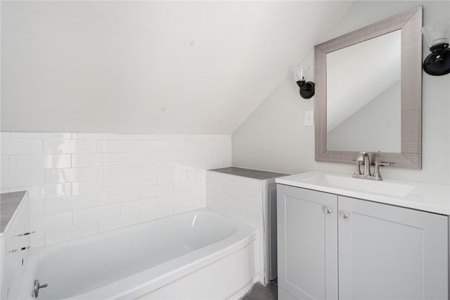 bathroom with vanity, vaulted ceiling, and a tub