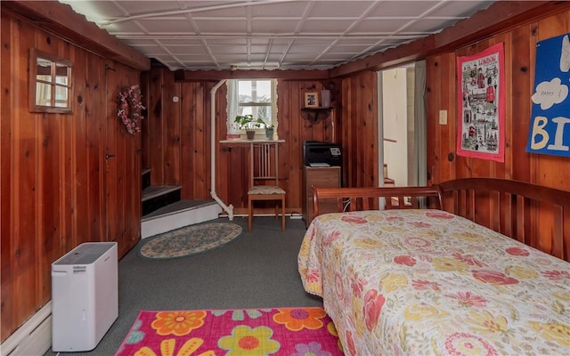 carpeted bedroom featuring wooden walls and baseboard heating