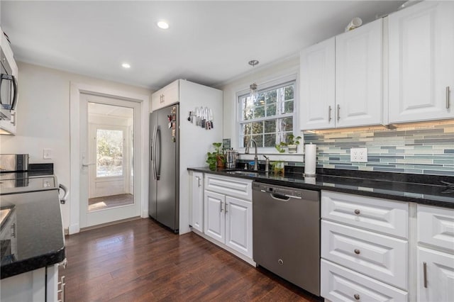 kitchen featuring appliances with stainless steel finishes, sink, white cabinets, and dark stone counters