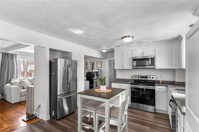 kitchen featuring dark stone countertops, stainless steel appliances, dark hardwood / wood-style floors, and white cabinets