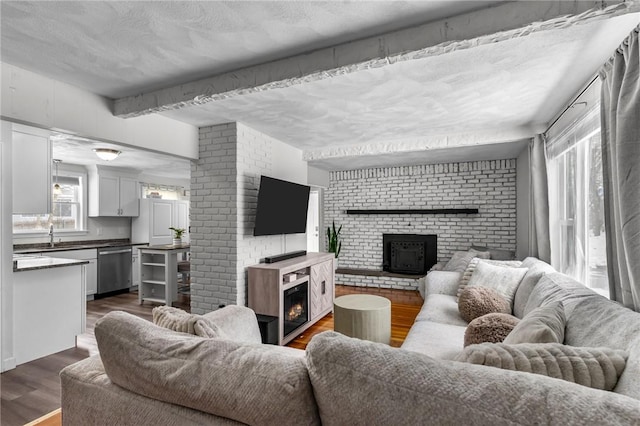 living room featuring dark hardwood / wood-style floors, brick wall, a healthy amount of sunlight, and a fireplace