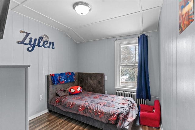 bedroom with lofted ceiling, radiator heating unit, and dark hardwood / wood-style floors