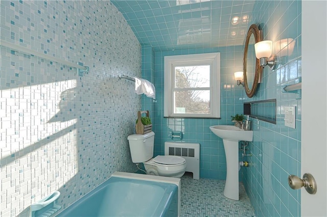 bathroom with tile patterned floors, toilet, tile walls, a bath, and radiator