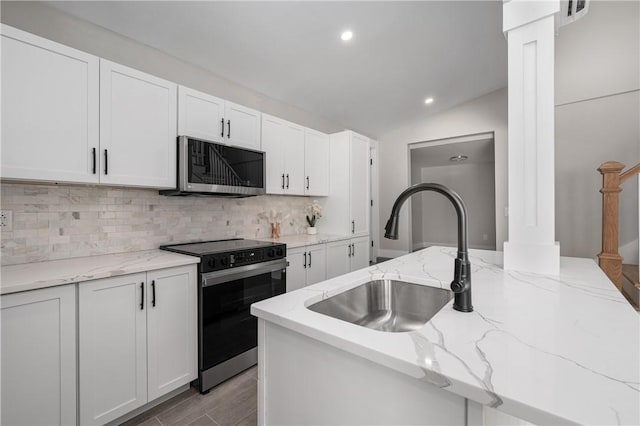 kitchen featuring appliances with stainless steel finishes, sink, backsplash, white cabinets, and light stone counters