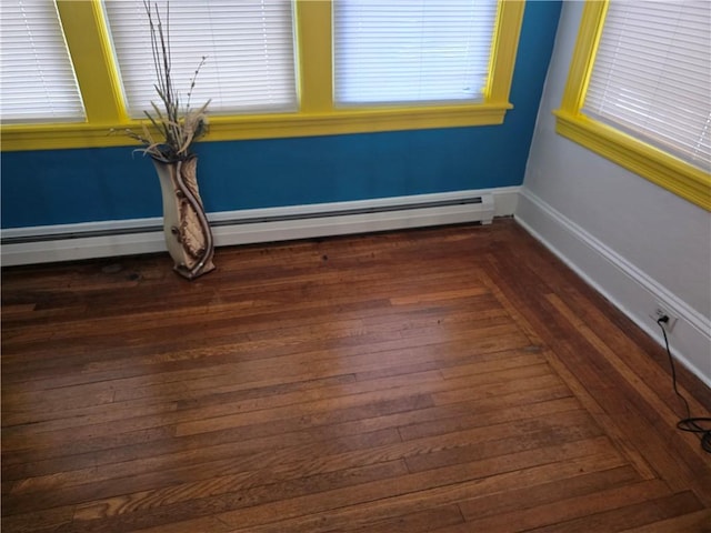 unfurnished room with dark hardwood / wood-style floors and a baseboard heating unit