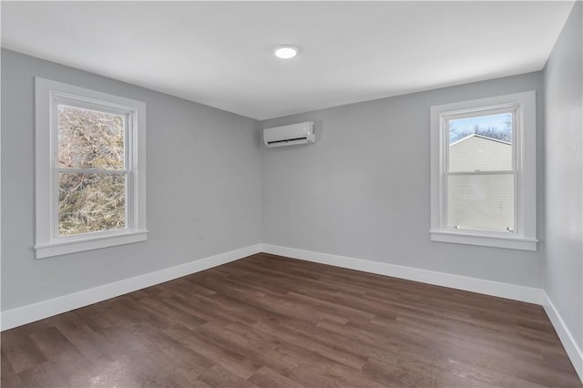 spare room featuring dark wood-type flooring, a wealth of natural light, and a wall mounted AC