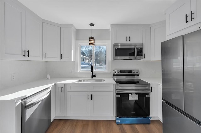 kitchen featuring sink, white cabinetry, dark hardwood / wood-style floors, pendant lighting, and stainless steel appliances