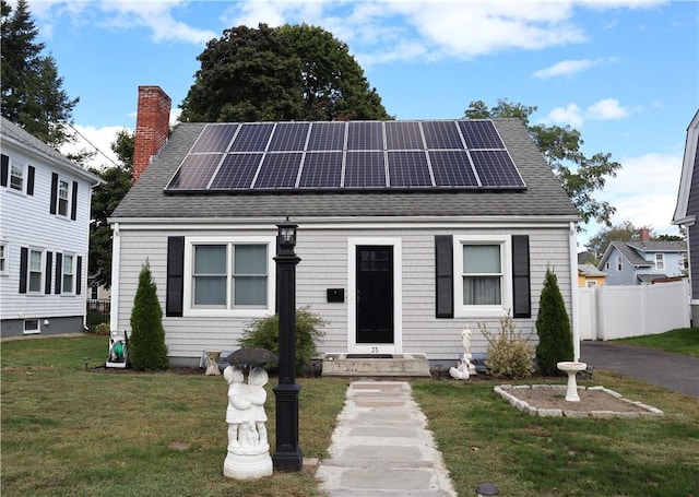 view of front of property featuring a front yard and solar panels