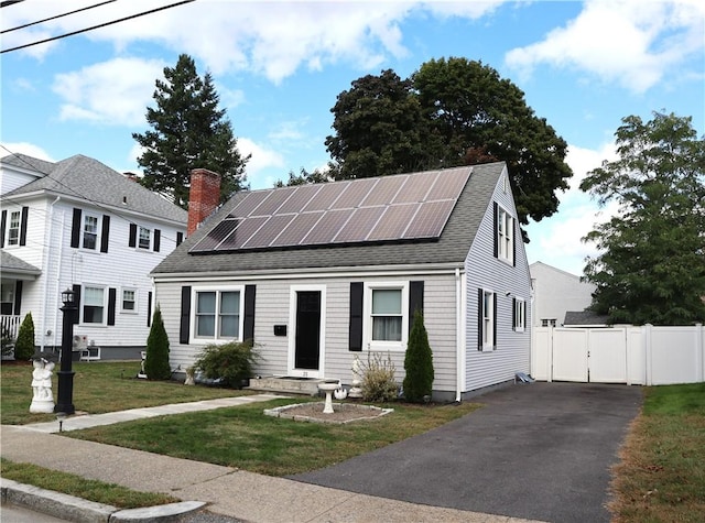 view of front of house with a front lawn and solar panels