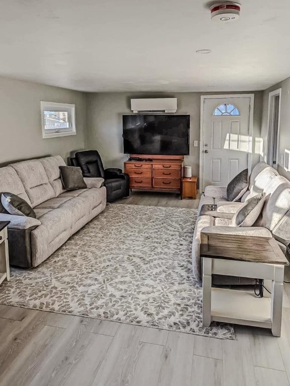 living room with light hardwood / wood-style flooring and an AC wall unit