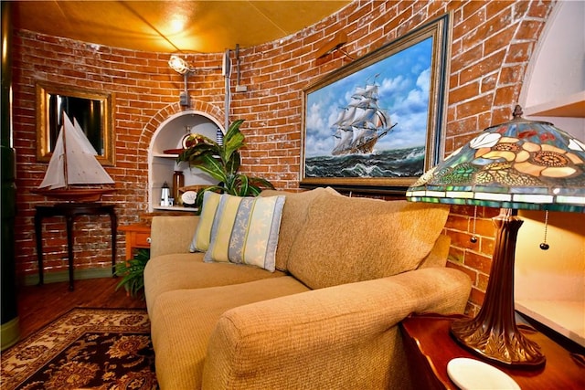 living room with hardwood / wood-style flooring and brick wall