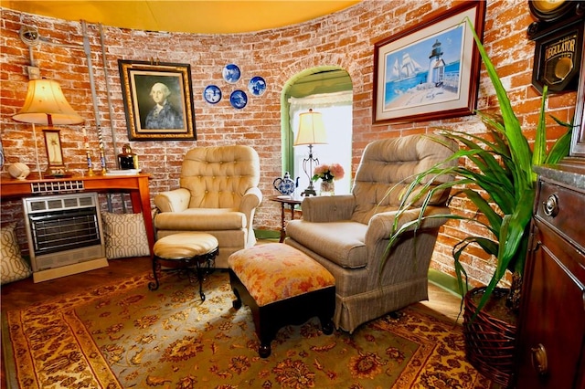 sitting room with brick wall, heating unit, and a fireplace