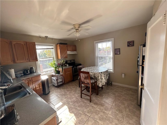 kitchen with light tile patterned floors, a wealth of natural light, stainless steel range with electric stovetop, and under cabinet range hood