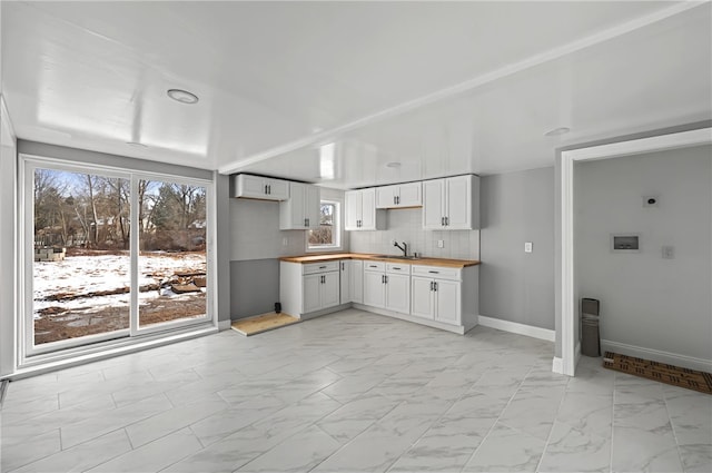 kitchen featuring tasteful backsplash, wood counters, sink, and white cabinets