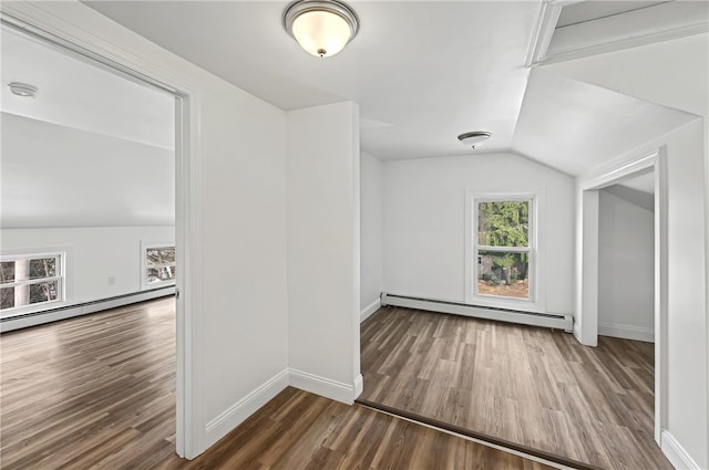 empty room featuring baseboard heating, lofted ceiling, and dark hardwood / wood-style floors