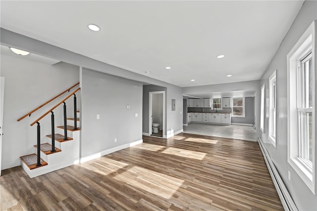 unfurnished living room featuring a baseboard heating unit and dark hardwood / wood-style flooring