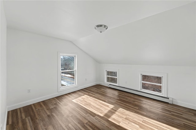 additional living space with dark wood-type flooring, a baseboard radiator, and vaulted ceiling