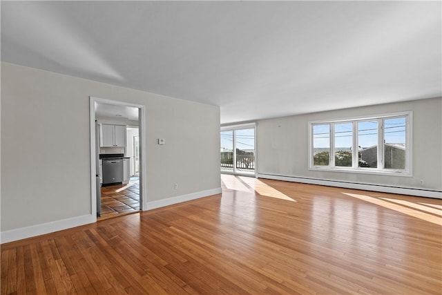 unfurnished living room with baseboard heating, wood-type flooring, and baseboards