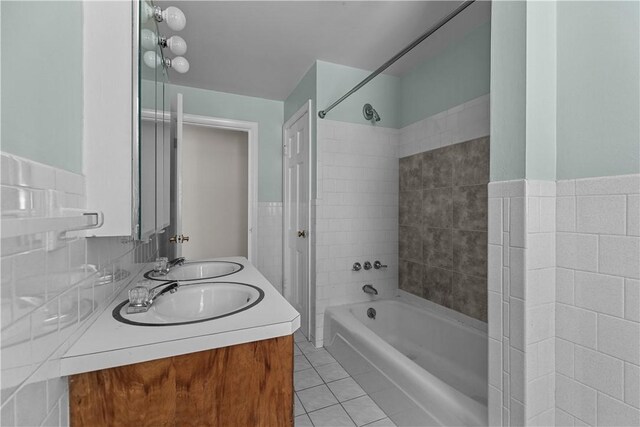 full bathroom with tile patterned flooring, tile walls, a sink, and shower / tub combination