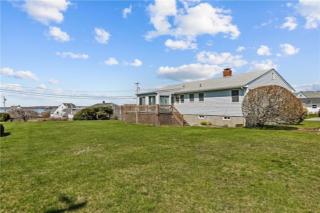 back of house featuring a chimney, a wooden deck, a yard, and stairs
