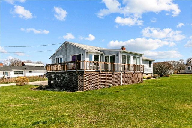 back of property featuring a lawn, a chimney, and a deck