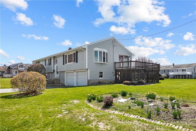 exterior space featuring an attached garage, a lawn, aphalt driveway, and a deck