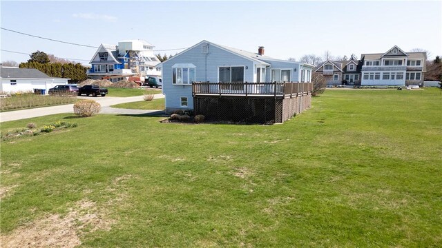 back of house featuring a wooden deck, driveway, and a yard