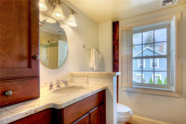 bathroom featuring plenty of natural light, toilet, and vanity