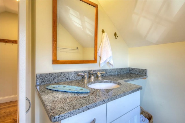 bathroom with vanity, hardwood / wood-style flooring, and vaulted ceiling