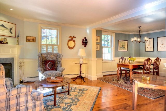 interior space featuring a tiled fireplace, crown molding, light hardwood / wood-style flooring, and baseboard heating