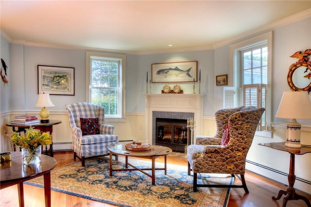 sitting room with a tile fireplace, crown molding, a baseboard heating unit, and hardwood / wood-style floors