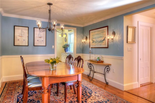 dining space with hardwood / wood-style floors, a notable chandelier, and ornamental molding