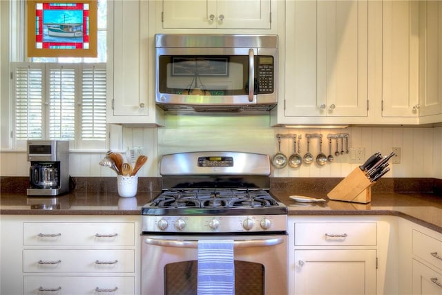 kitchen with tasteful backsplash, appliances with stainless steel finishes, and white cabinets