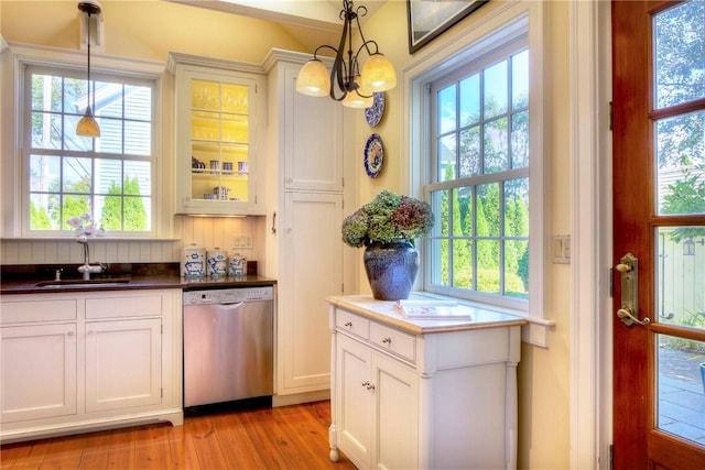 interior space with sink, white cabinetry, light wood-type flooring, stainless steel dishwasher, and pendant lighting