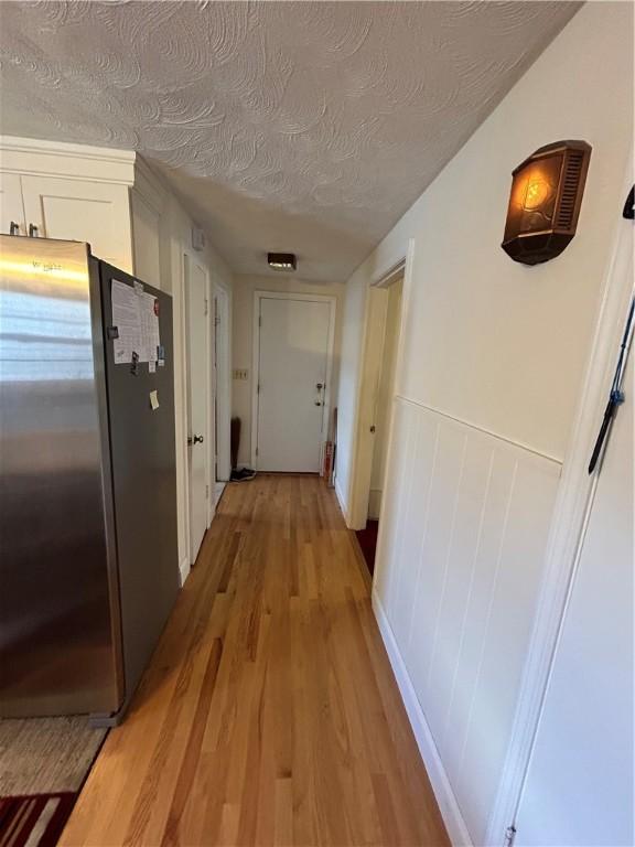 hall featuring light hardwood / wood-style floors and a textured ceiling