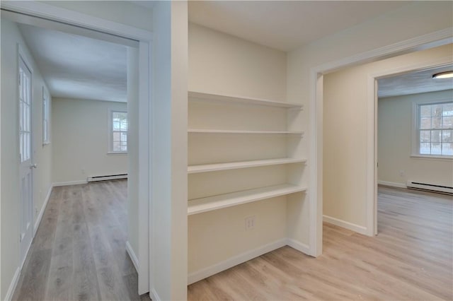 corridor featuring built in shelves, light hardwood / wood-style floors, and baseboard heating