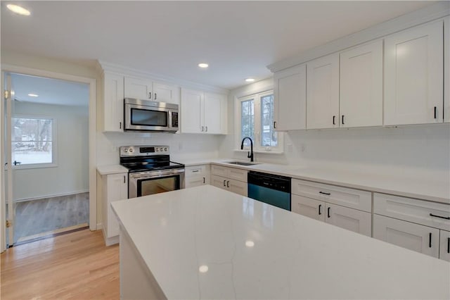 kitchen featuring sink, stainless steel appliances, light hardwood / wood-style floors, and white cabinets