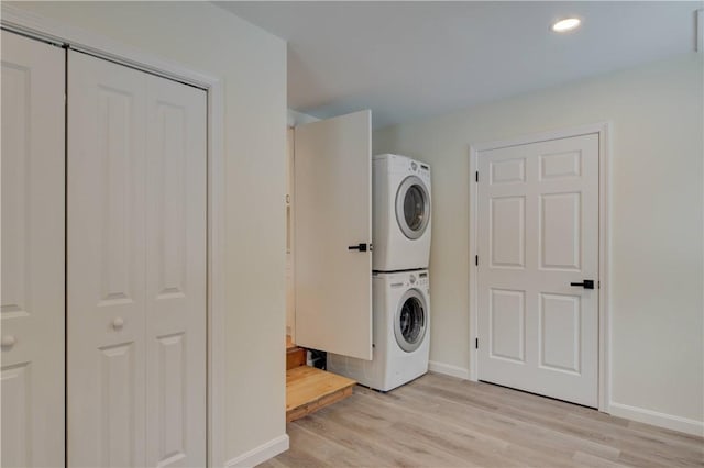 washroom with stacked washer and dryer and light hardwood / wood-style floors