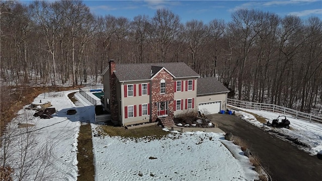 view of front of home featuring a garage, aphalt driveway, a chimney, and fence