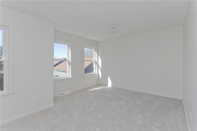 spare room with carpet, visible vents, and baseboards