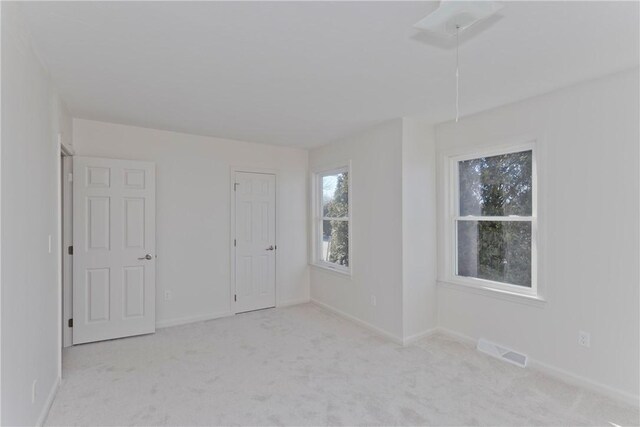 unfurnished bedroom featuring baseboards, visible vents, and light colored carpet