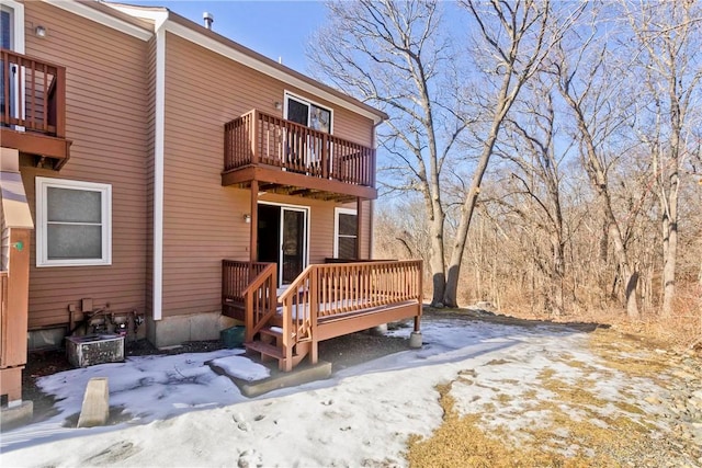 snow covered rear of property with a balcony