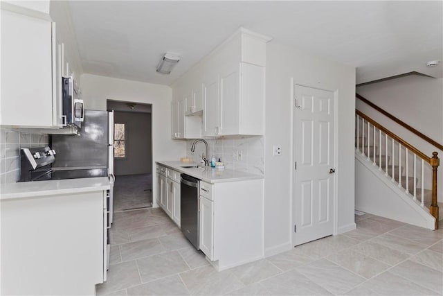 kitchen with tasteful backsplash, light countertops, appliances with stainless steel finishes, white cabinets, and a sink