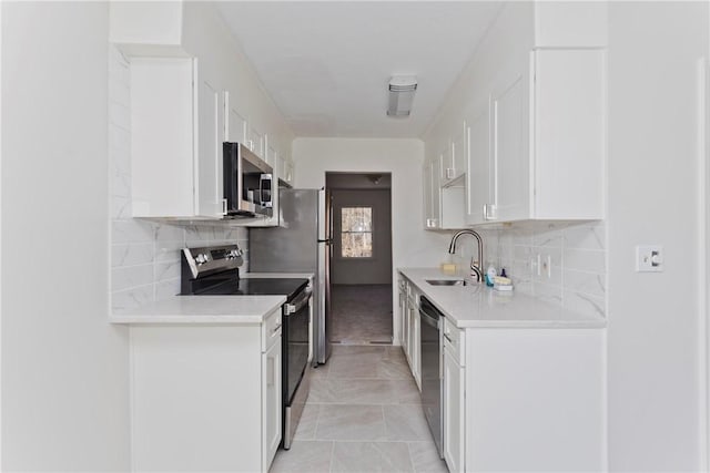 kitchen with decorative backsplash, appliances with stainless steel finishes, light countertops, white cabinetry, and a sink