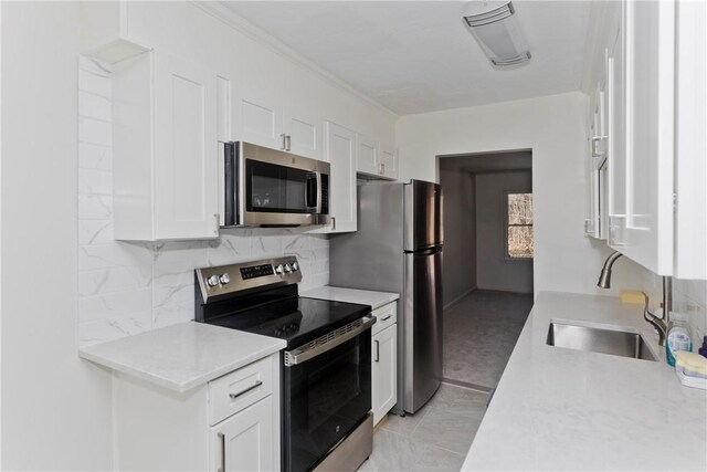 kitchen with light countertops, appliances with stainless steel finishes, a sink, and white cabinetry