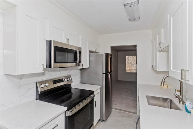 kitchen featuring stainless steel appliances, a sink, white cabinetry, light countertops, and backsplash