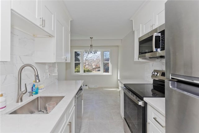 kitchen with light countertops, appliances with stainless steel finishes, a sink, and decorative backsplash