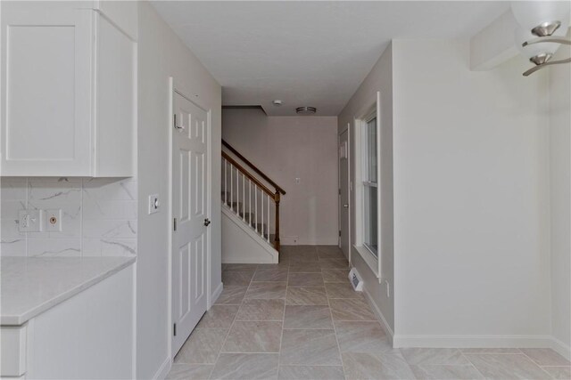 corridor featuring baseboards and stairway