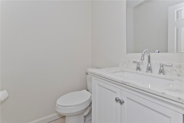 bathroom featuring baseboards, vanity, and toilet