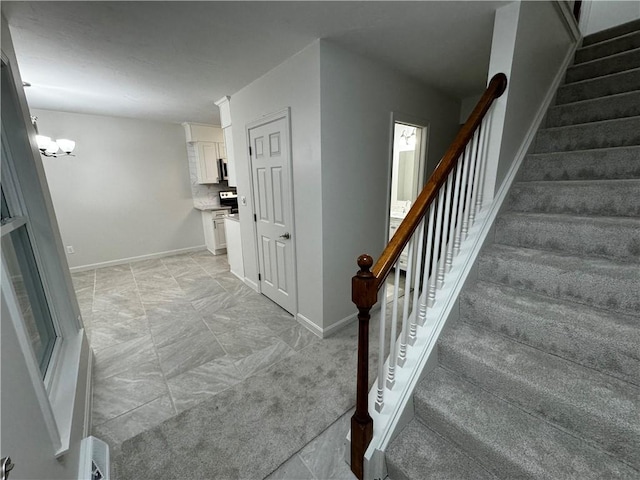 staircase featuring an inviting chandelier and baseboards